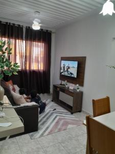 Dos niños sentados en una sala de estar viendo la televisión en Apartamento no centro de Cuiabá a 4 km do aeroporto, en Cuiabá