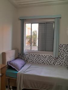 1 dormitorio con ventana, cama y silla en Apartamento no centro de Cuiabá a 4 km do aeroporto, en Cuiabá