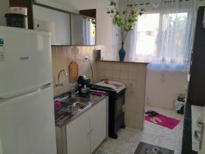 una pequeña cocina con fregadero y nevera. en Apartamento no centro de Cuiabá a 4 km do aeroporto, en Cuiabá