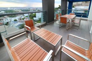 balcón con 2 bancos, mesa y sillas en Holiday Inn Queretaro Zona Diamante, an IHG Hotel, en Querétaro