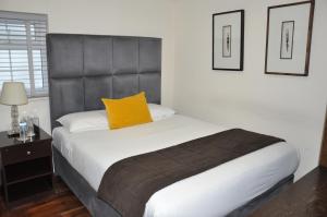 ein Schlafzimmer mit einem Bett mit gelbem Kissen darauf in der Unterkunft Nap Inn Savoro in Barnet