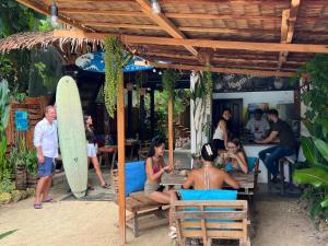 a group of people sitting at a restaurant with a surfboard at Wave retreat in General Luna