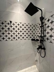 y baño con ducha y azulejos blancos y negros. en شقة أنيقة في العليا en Riad