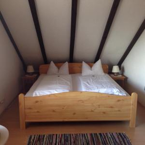 ein Holzbett mit weißer Bettwäsche und Kissen in einem Zimmer in der Unterkunft Landgasthof zum Stern in Elfershausen