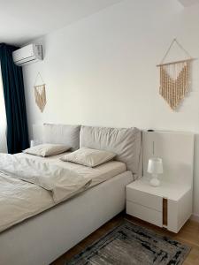 a white bedroom with a bed and a table at C-entral Apartments Bucharest with Private Parking in Bucharest