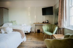 um quarto de hotel com duas camas e uma cadeira em The Grove Ferry Inn em Chislet