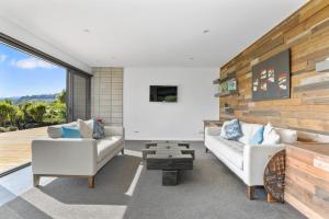 a living room with two white couches and a wooden wall at Lake Tarawera Gem in Rotorua