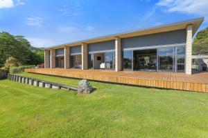 a house with a large deck in the grass at Lake Tarawera Gem in Rotorua