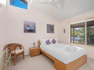 ein Schlafzimmer mit einem Bett, einem Stuhl und einem Fenster in der Unterkunft Beachwood in Emerald Beach