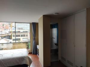 een slaapkamer met een bed en een groot raam bij apartasuite sector marly-chapinero-palermo in Bogota