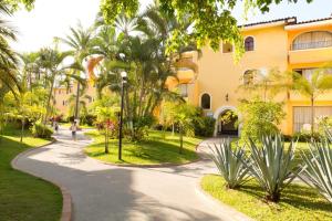 une passerelle traversant un parc en face d'un bâtiment dans l'établissement Costa Club Punta Arena - Desayuno Incluido, à Puerto Vallarta