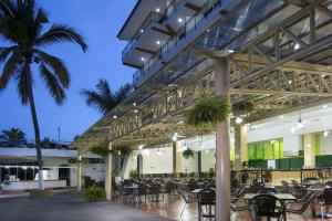 a patio with tables and chairs and a palm tree at Costa Club Punta Arena - Desayuno Incluido in Puerto Vallarta