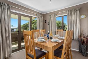 a dining room with a wooden table and chairs at The Sun Capsule - Ohope Beach Holiday Home in Ohope Beach