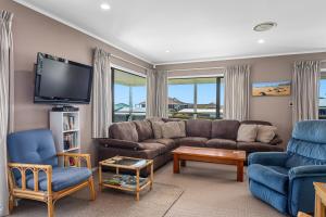 a living room with a couch and chairs and a tv at The Sun Capsule - Ohope Beach Holiday Home in Ohope Beach