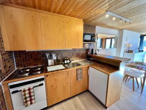 una cucina con armadi in legno, lavandino e piano cottura di THE ALPINE STUDIO on the ski slopes - by the lake - Alpe des Chaux - Gryon a Gryon