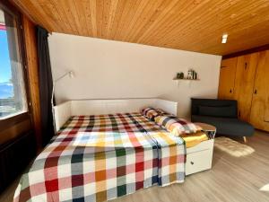 um pequeno quarto com uma cama e uma cadeira em THE ALPINE STUDIO on the ski slopes - by the lake - Alpe des Chaux - Gryon em Gryon