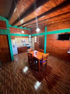 a room with a wooden table and a kitchen at Departamentos La Familia in Mina Clavero