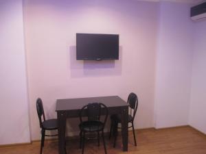a dining room table with chairs and a tv on a wall at Orbi Residence 22 Floor in Batumi