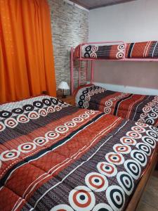 two twin beds in a room with orange curtains at Departamentos La Familia in Mina Clavero