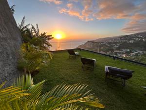 eine Gruppe von Stühlen auf dem Rasen mit Sonnenuntergang in der Unterkunft Art Sunset Luxuary Villa in Ribeira Brava