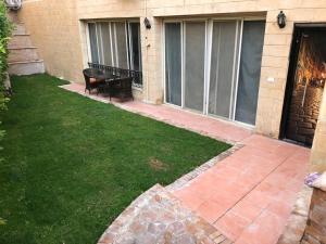 patio z ławką w trawie obok budynku w obiekcie Ground floor villa with private garden, parking and shared swimming pool w mieście El `Agûza