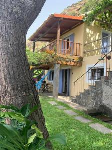 a house with a balcony and a tree at Chalet Tropical in Arco da Calheta