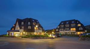two large buildings in a parking lot at night at Dorint Strandresort & Spa Westerland/Sylt in Westerland