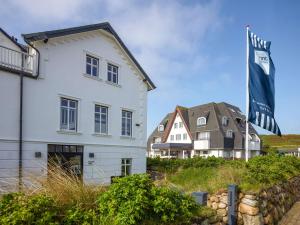 a white house with a flag next to houses at Dorint Strandresort & Spa Westerland/Sylt in Westerland