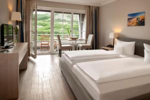 a hotel room with two beds and a dining table at Dorint Strandresort & Spa Westerland/Sylt in Westerland