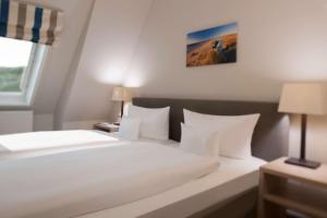 a bedroom with a large white bed with white pillows at Dorint Strandresort & Spa Westerland/Sylt in Westerland