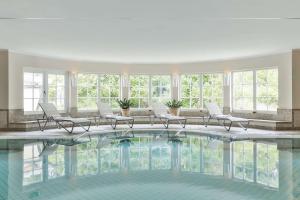 a large pool in a building with chairs and windows at Dorint Strandresort & Spa Westerland/Sylt in Westerland