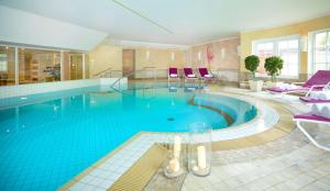 a large swimming pool with blue water in a building at Dorint Strandresort & Spa Westerland/Sylt in Westerland