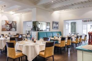 a dining room with white tables and chairs at Dorint Strandresort & Spa Westerland/Sylt in Westerland