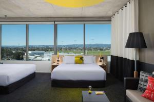 Habitación de hotel con 2 camas y ventana grande. en Atura Adelaide Airport en Adelaida