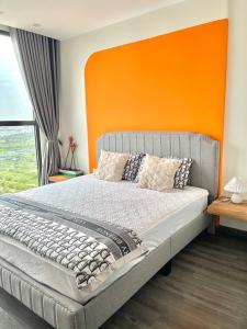 ein Schlafzimmer mit einem großen Bett mit einem orangefarbenen Kopfteil in der Unterkunft R102 Vinhomes Ocean Park homestay in Hanoi
