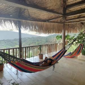 Nature Harmony Retreat in Tierra Bomba - Your Sustainable Escape في كارتاهينا دي اندياس: امرأة مستلقية على أرجوحة على الشرفة