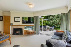 a living room with a couch and a fireplace at Kohekohe Garden Cottage - Waikanae Holiday Home in Waikanae