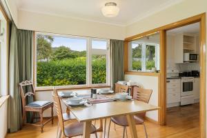 a kitchen and dining room with a table and chairs at Kohekohe Garden Cottage - Waikanae Holiday Home in Waikanae