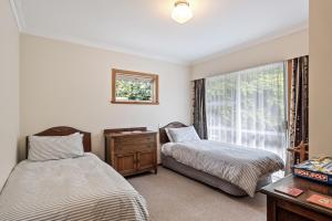 Duas camas num quarto com uma janela em Kohekohe Garden Cottage - Waikanae Holiday Home em Waikanae