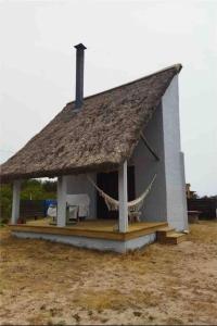 a small hut with a grass roof with a net at Casa en Valizas a 250m del mar in Barra de Valizas