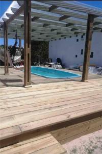 a swimming pool with a wooden deck and a swing at Casa en Valizas a 250m del mar in Barra de Valizas