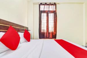 - un lit rouge et blanc avec des oreillers rouges dans l'établissement Flagship Hotel Moonshine Inn, à New Delhi