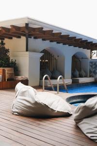 een houten terras met kussens en een zwembad bij Los Pilares Hotel in Oaxaca City