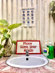 um lavatório da casa de banho com uma placa que diz por favor lave as mãos em Hidden Garden Pensione em El Nido