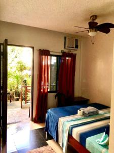 Schlafzimmer mit einem Bett und einem Fenster mit roten Vorhängen in der Unterkunft Hidden Garden Pensione in El Nido