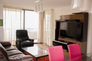 sala de estar con sillas rosas y TV en Departamento royal marine, en Iquique