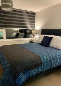 um quarto com uma cama com um cobertor azul em Departamento Excelente Ubicación em Concepción