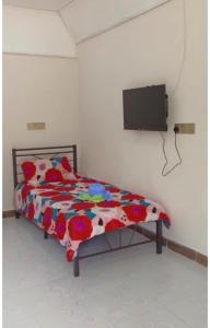 1 dormitorio con 1 cama y TV en la pared en D'DUSUN RAUDHAH HOMESTAY, en Baling