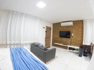 a bedroom with a couch and a television in it at Flat na natureza in Bonito