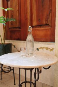 a glass bottle on a table with glasses on it at Los Pilares Hotel in Oaxaca City